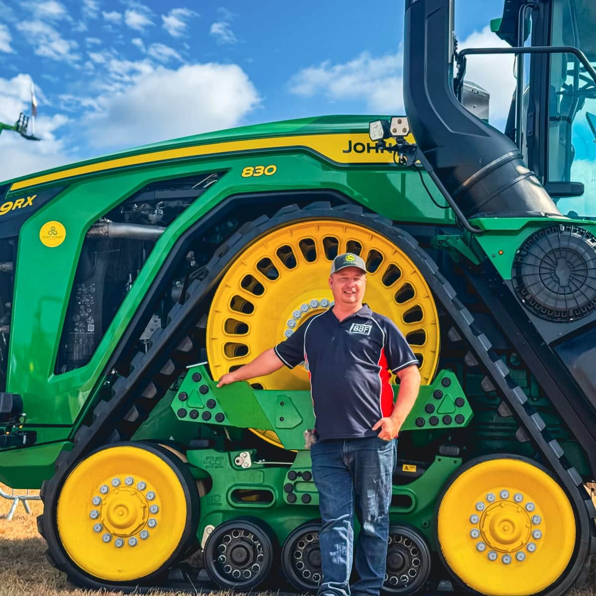 Tom Oswald standing in front of a John Deere 9RX 830 tractor