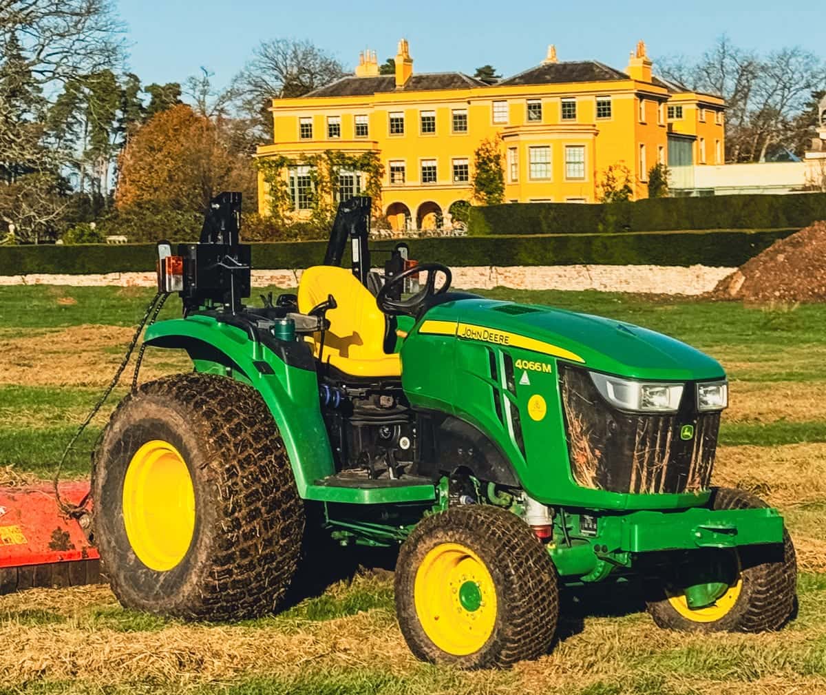 Compact John Deere 4066M tractor with a flail topper on a freshly topped paddock