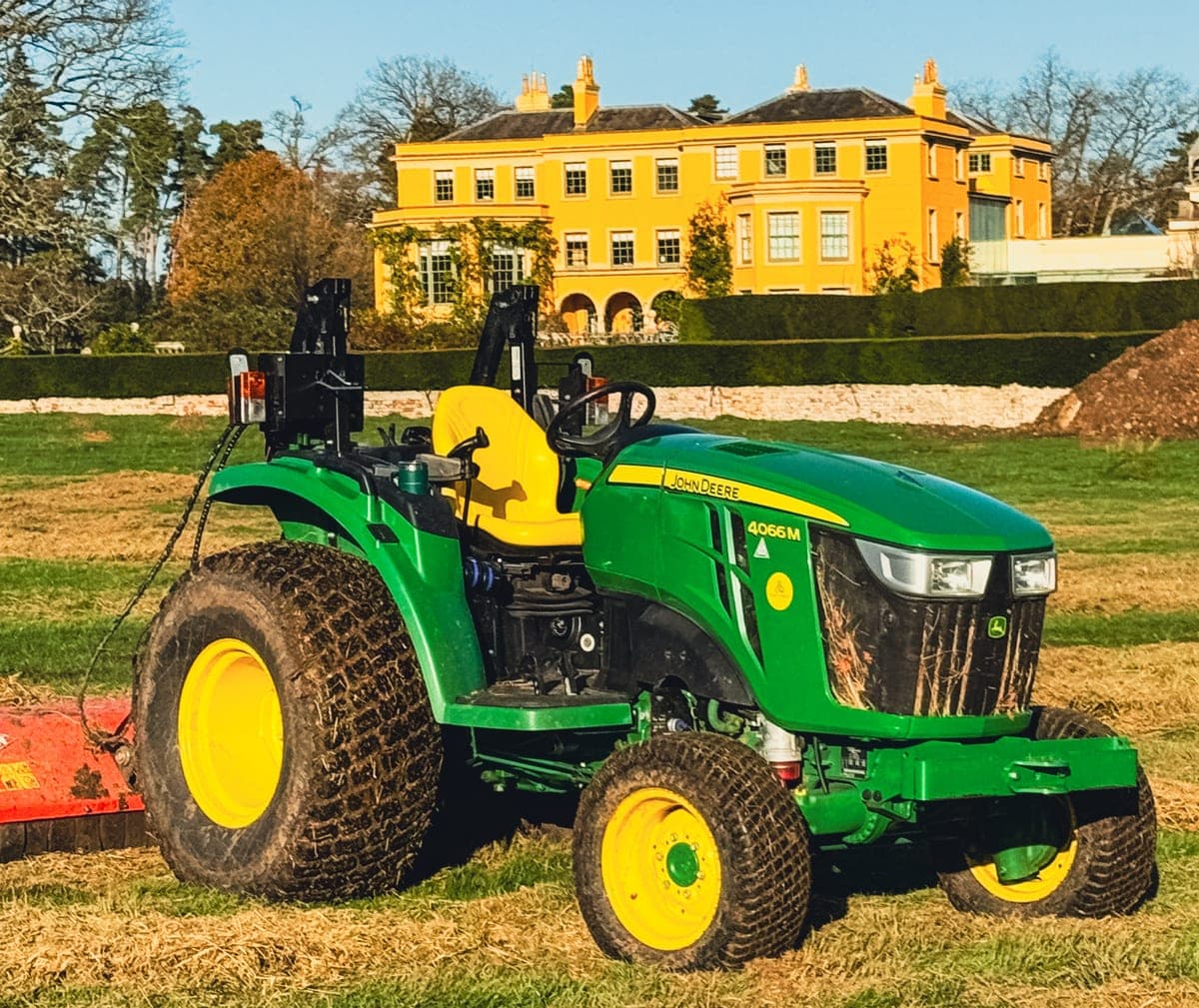 Compact John Deere 4066M tractor with a flail topper on a freshly topped paddock